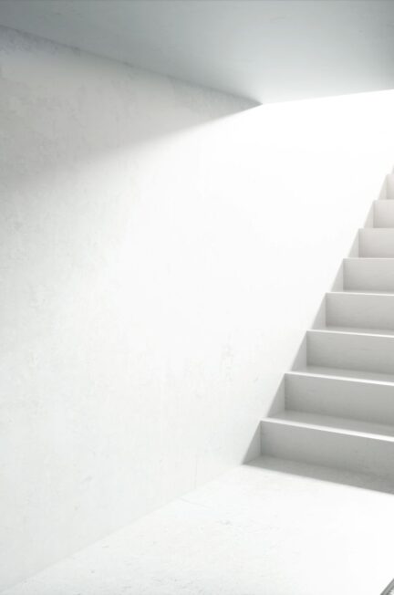 Moderne weiße Betontreppe mit Tageslicht von oben, Beispiel für minimalistisches Design beim Treppen planen